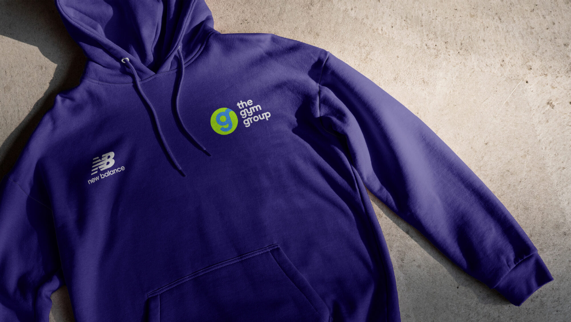 A dark blue hooded sweatshirt with the Gym Group logo.