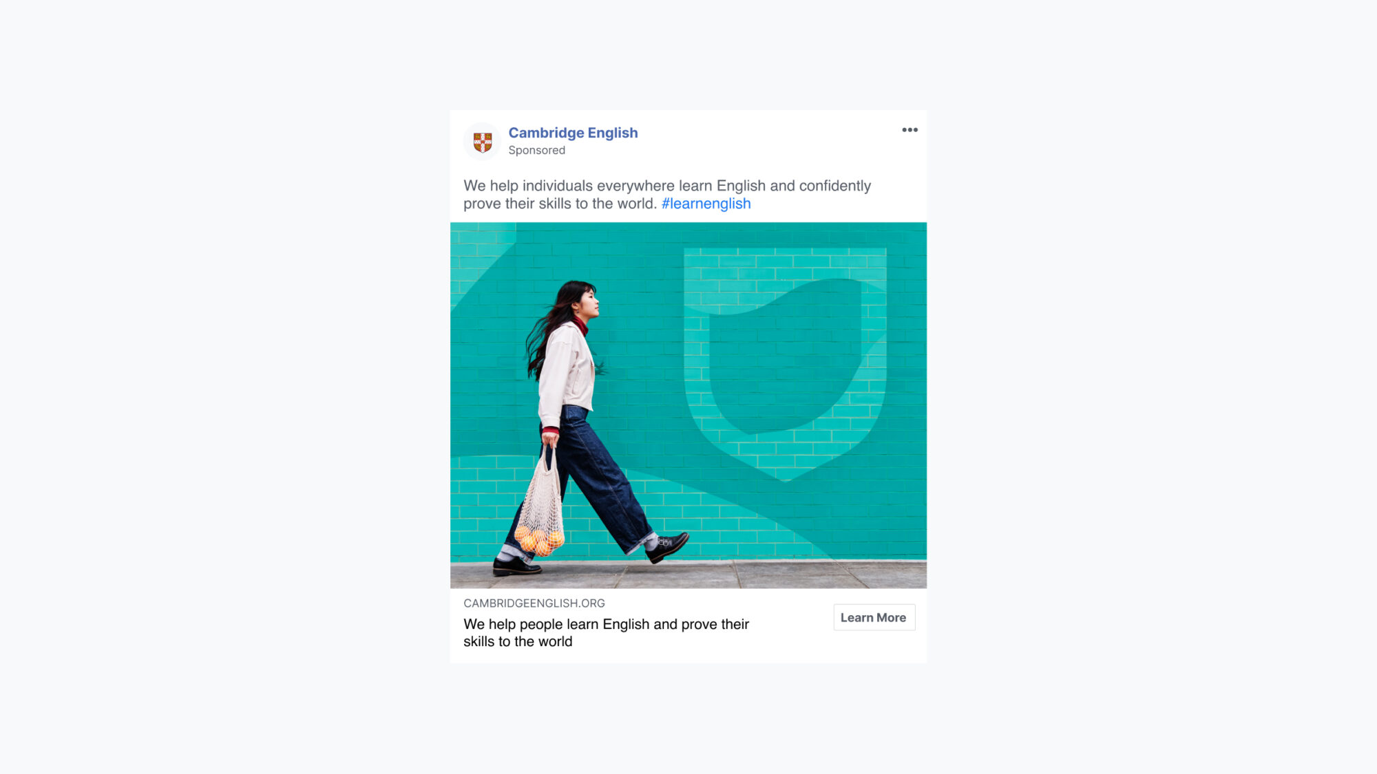 A social post with a photo of a woman walking past a bright Cambridge blue wall that shows the logo as part of the street art.
