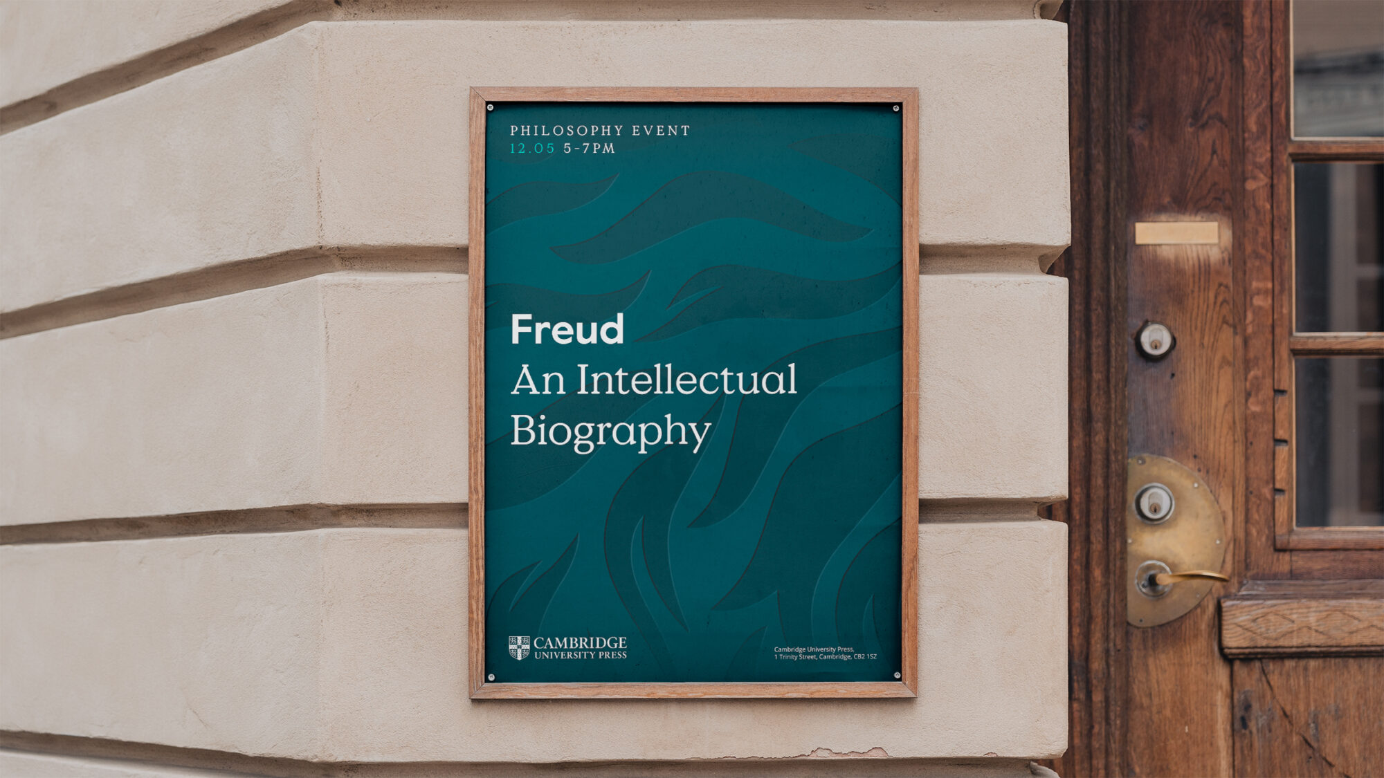 A street with a graphic Cambridge Press poster pasted on the wall. The poster features a title for a book “Freud, an intellectual biography”