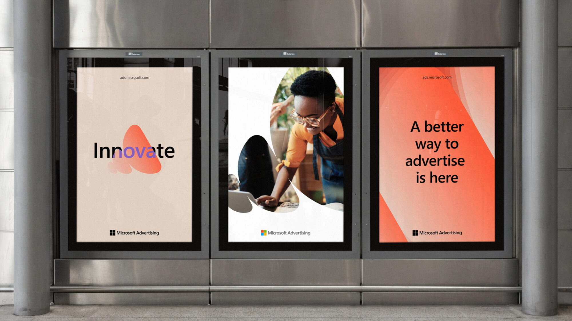 A street with three graphic Microsoft Advertising screens on the wall. The middle screen features a woman working masked in the brand pattern and the title “A better way to advertise is here”