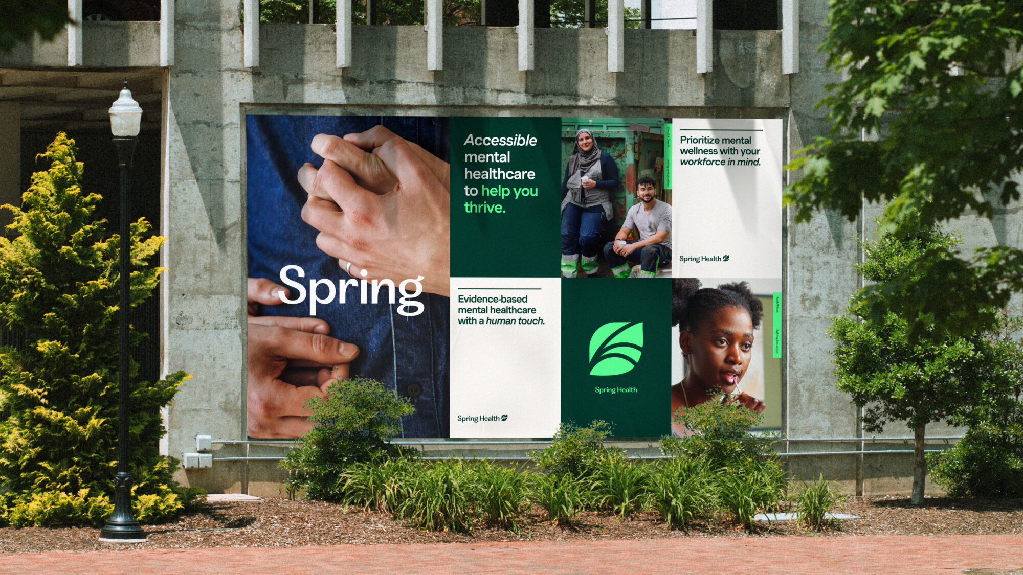 A street with a graphic Spring Health poster pasted on the wall. The largest poster features two people up close holding hands.