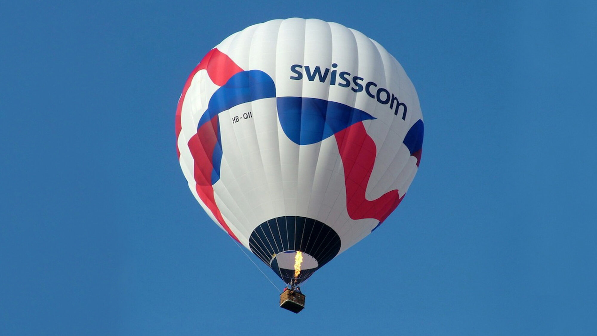 A hot air balloon with the Swisscom logo and word mark printed on it.