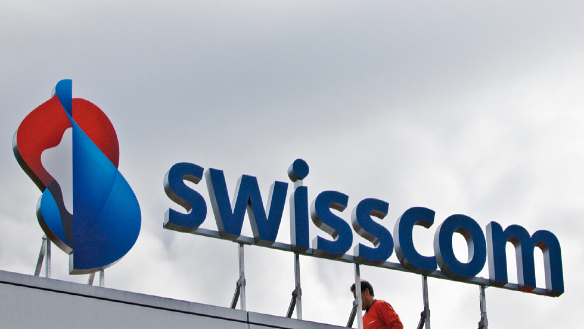 The roof of a building with a large Swisscom logo on it.