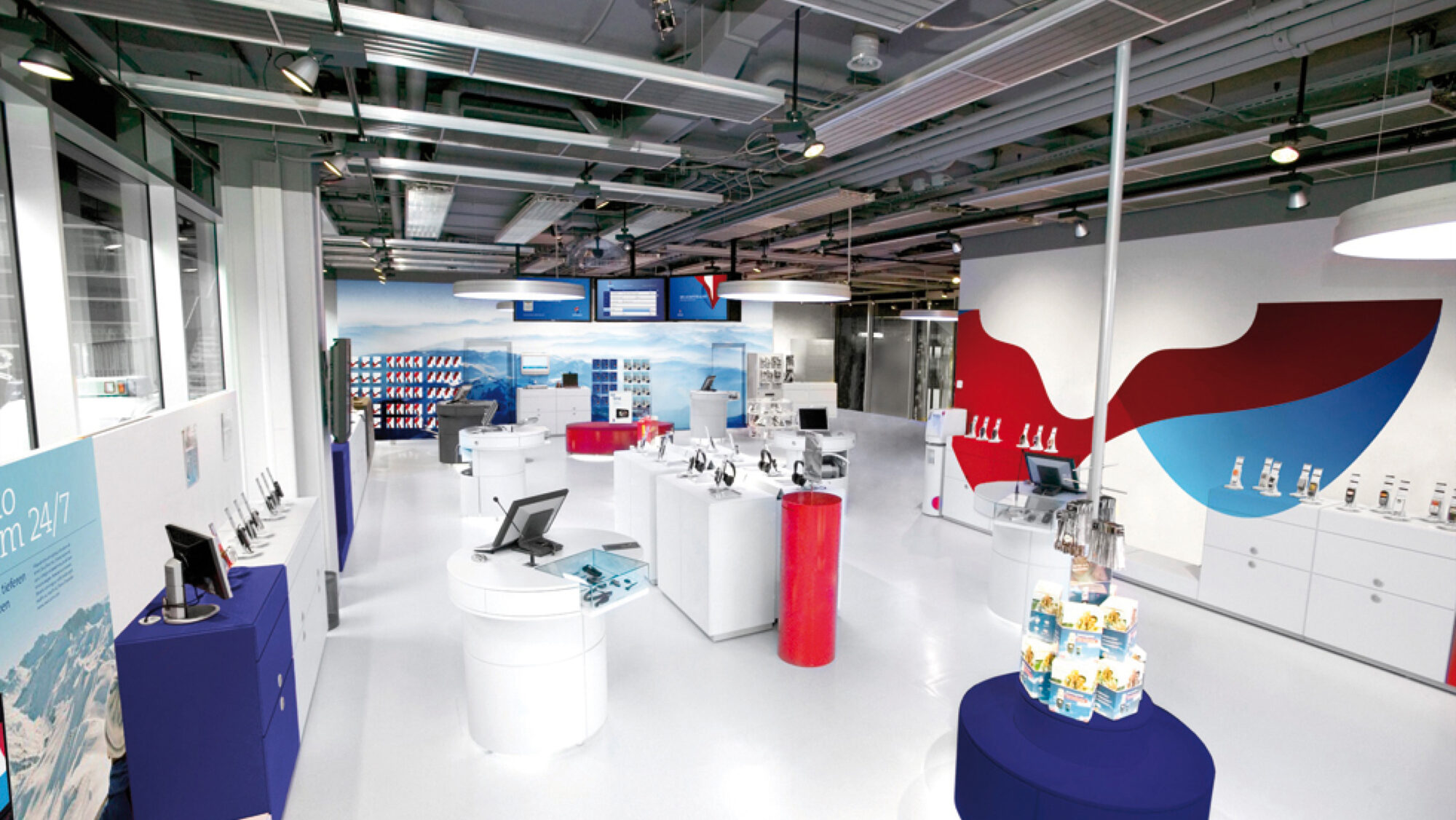 A Swisscom shop interior showing different devices on display and the logo textures printed on the walls.