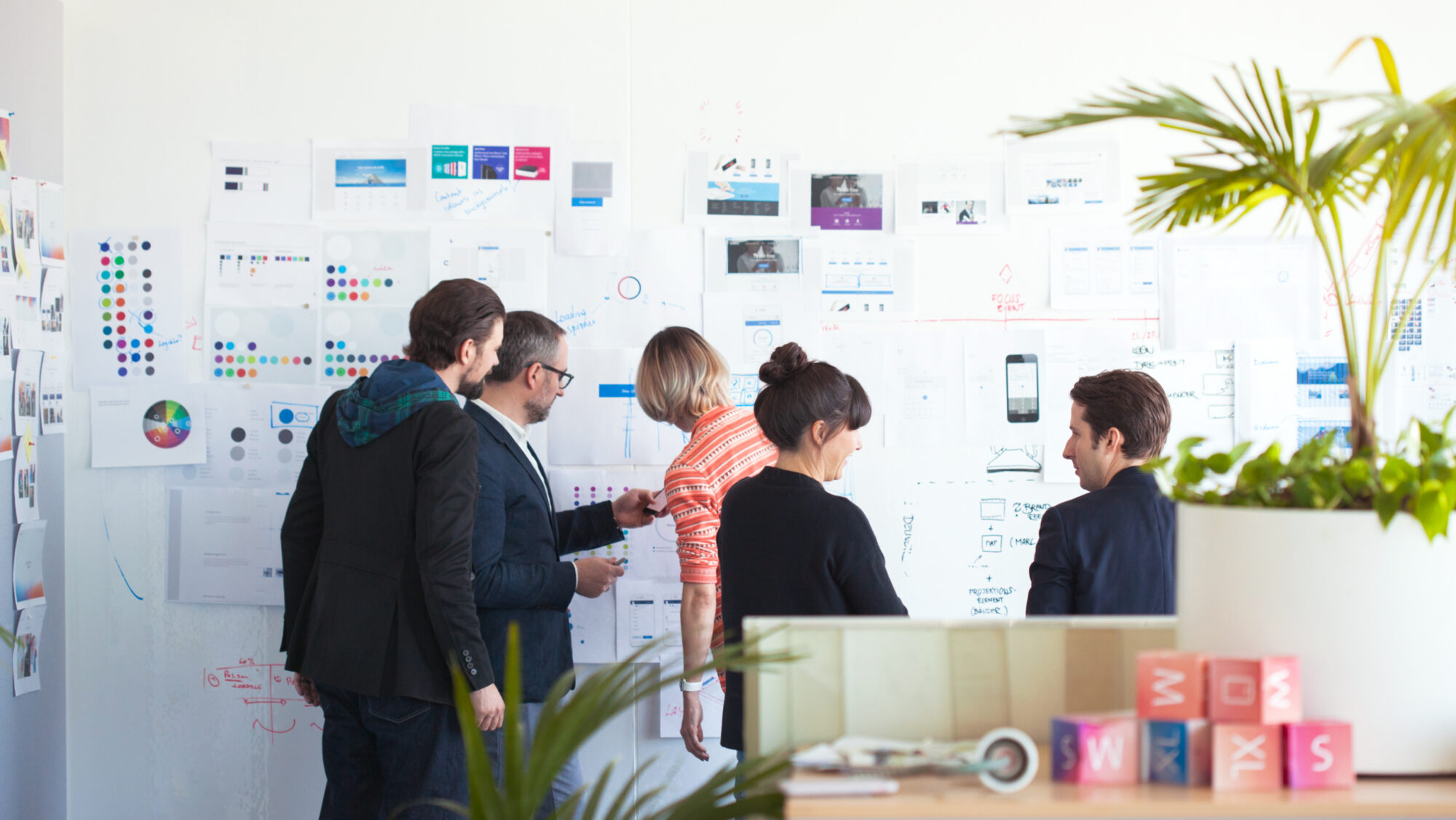 A group of people standing in front of a wall with workshop material.